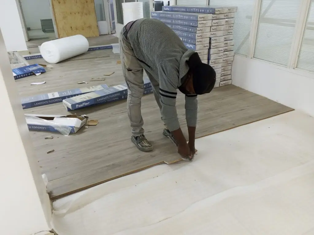 Technician laying SPC flooring planks with precision in a renovated room