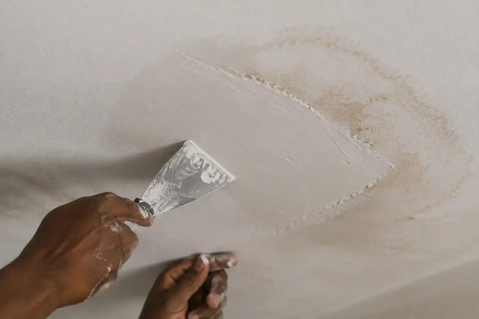 Gypsum ceiling maintenance in Kenya showing a technician patching a water-damaged section of ceiling